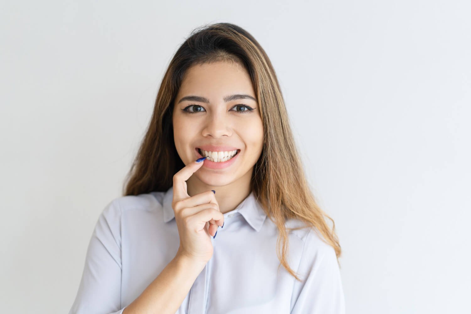 Mulher sorridente aponta para os dentes alinhados, demonstrando o conforto do Invisalign na Croi Odontologia em Brasília.