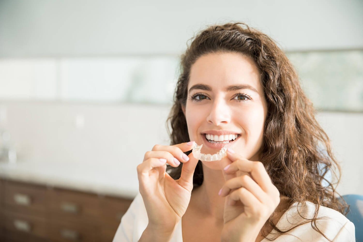 Mulher segurando alinhador invisível transparente. Representa a troca de aparelho fixo na Croi Odontologia, Asa Norte, Brasília