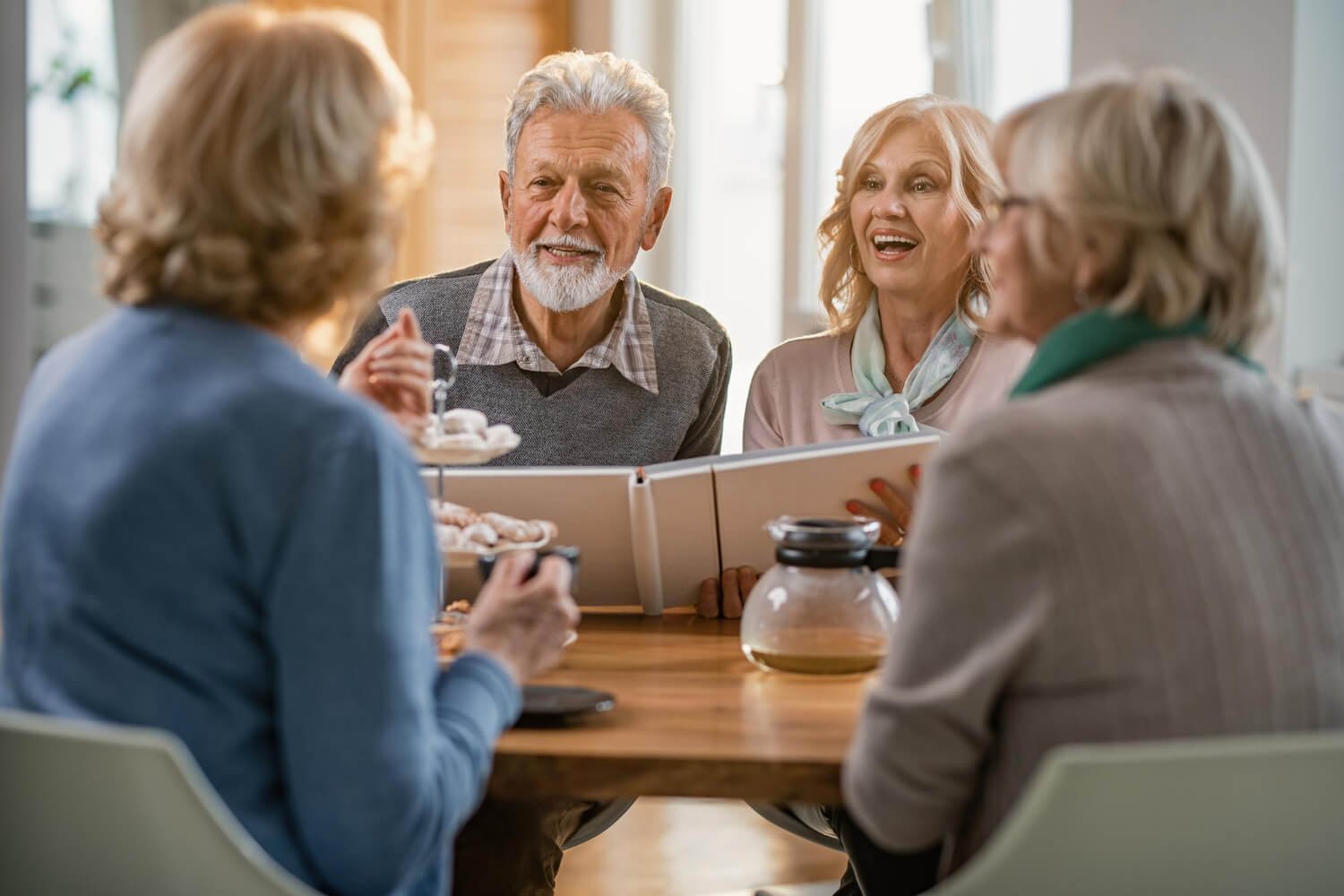 Idosos sorrindo ao redor de mesa, mostrando a segurança e longevidade do implante dentário na Clínica Croi Odontologia, Asa Norte.