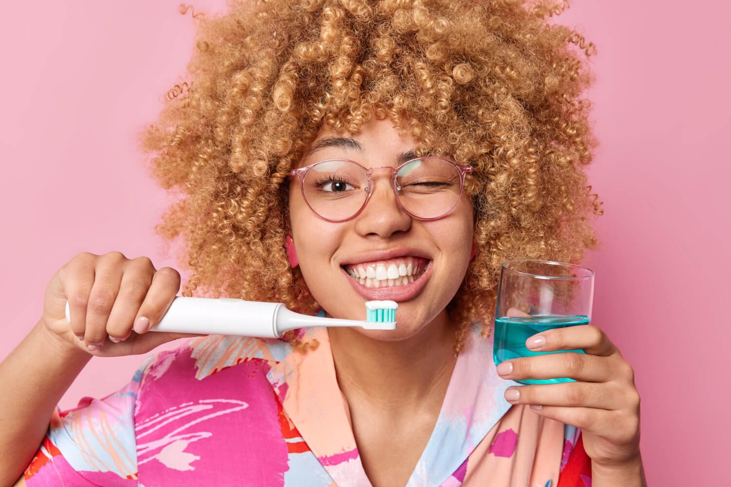 Mulher sorrindo segura escova elétrica e enxaguante bucal na Croi Odontologia, especialista em alinhadores invisíveis na Asa Norte.